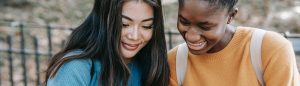 Students smiling together at phone screen.